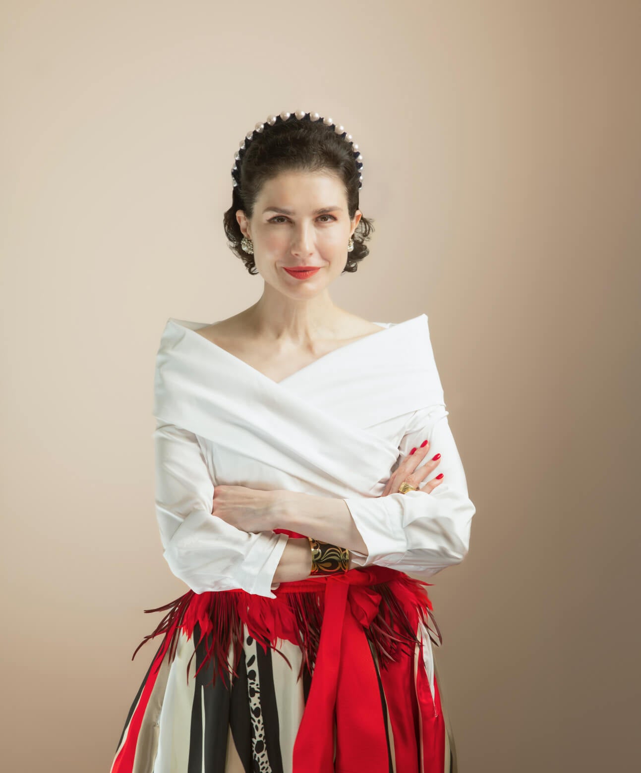 Board certified dermatologist and longevity skincare expert dr. Liv Kraemer smiling with her arms crossed, standing in front of a white background.