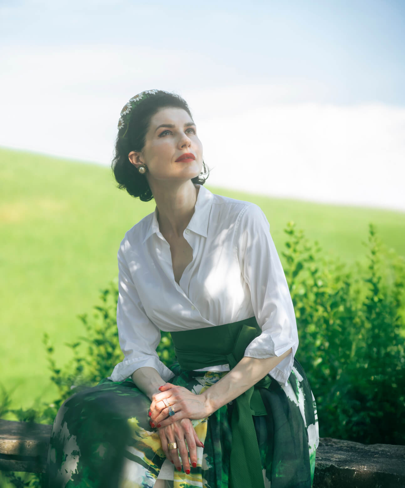 Board certified dermatologist and longevity skincare expert Dr. Liv Kraemer standing in nature, having her leg propped up, looking into the distance