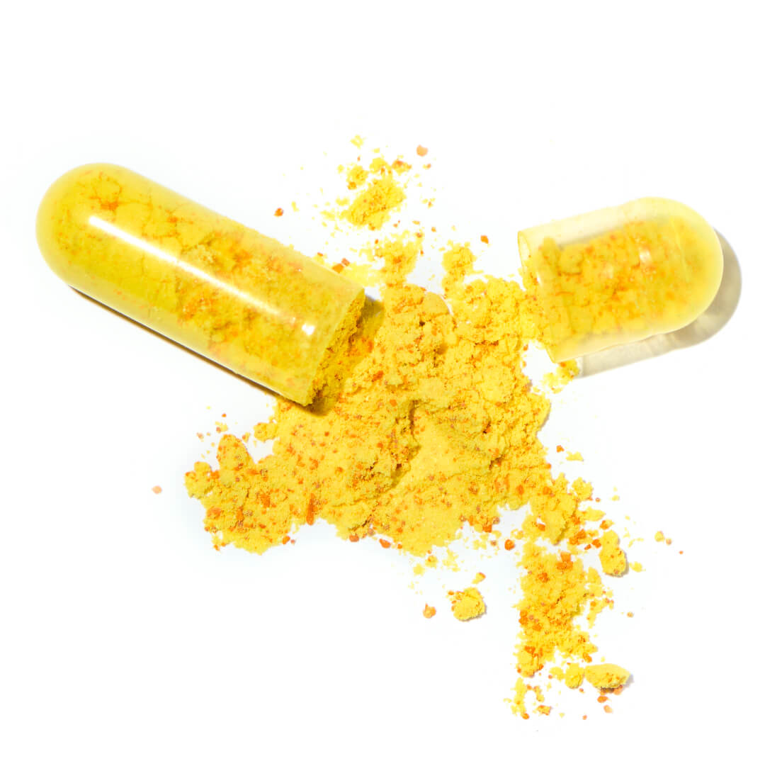 A broken capsule of board certified dermatologist Dr. Liv Kraemers' Calm Advanced Skin Supplement, showing the yellow powder, against a white background.