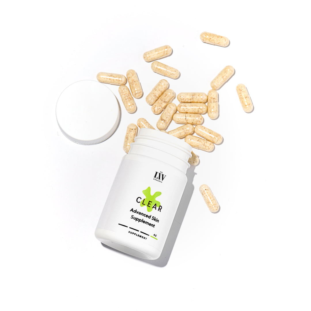 The Clear Advanced Skin Supplement bottle lying on a white background with an open lid, letting the orange capsules fall out of the bottle; developed by board certified dermatologist and skincare longevity expert Dr. Liv Kraemer 